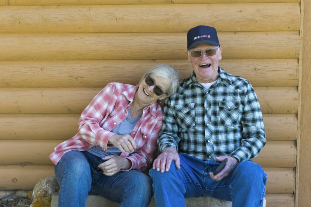 An elderly couple sitting together outdoors, smiling